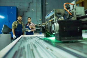 Engineers Using CNC Machine At Factory With The Latest Laser Cutting Technologies Engineers Using CNC Machine At Factory With The Latest Laser Cutting Technologies